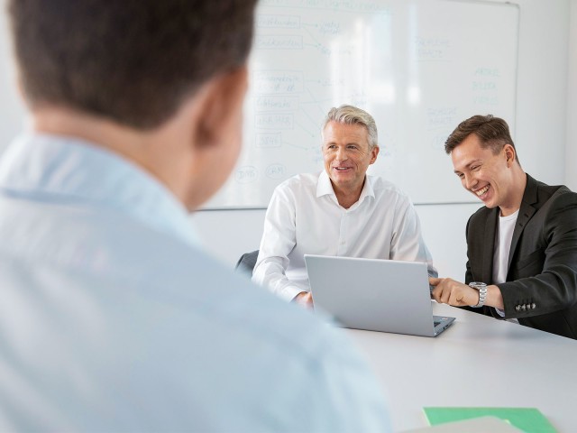 Männer in gemischter Altersgruppe lachend im Meeting