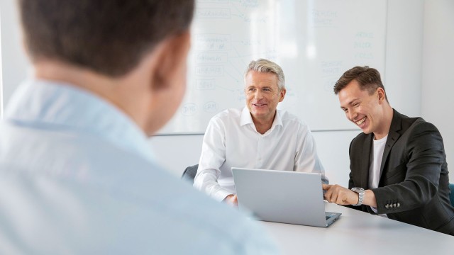 Männer in gemischter Altersgruppe lachend im Meeting