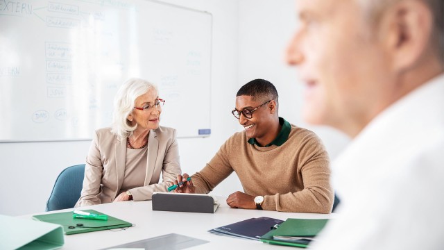 Eine ältere Frau und ein junger Mann sitzen zusammen in einem Meeting