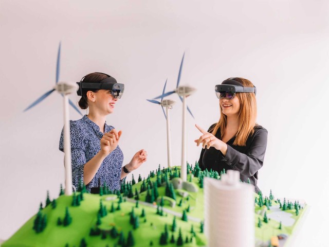 Zwei Frauen mit VR-Brillen vor einem Windradmodell