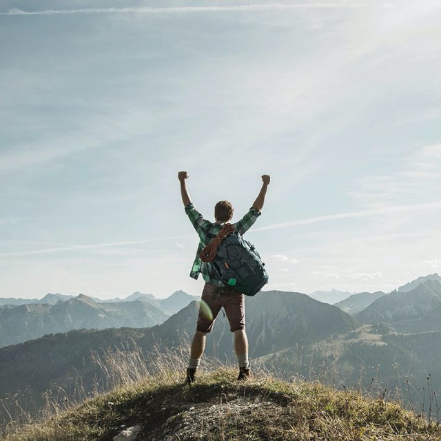 Man stands proudly on the top of a mountain