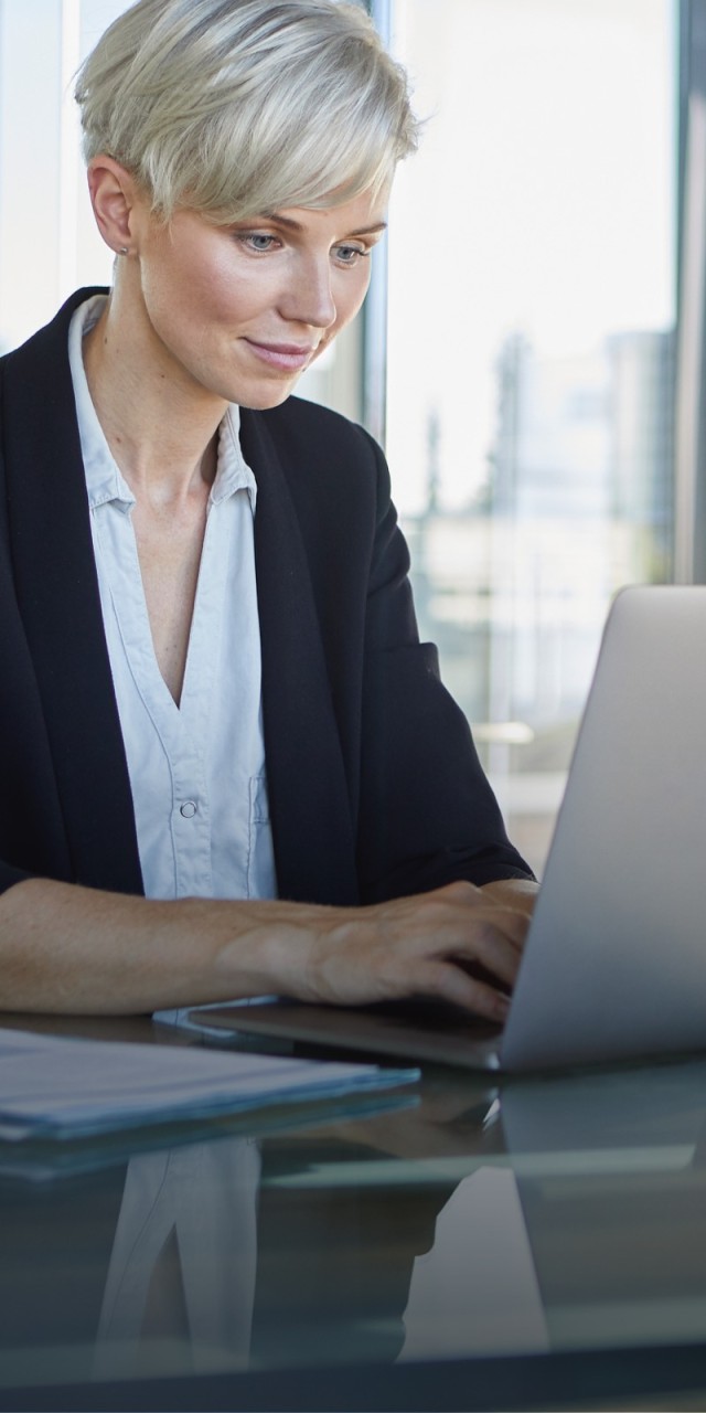 Business-Frau sitzt am Schreibtisch und arbeitet am Laptop  