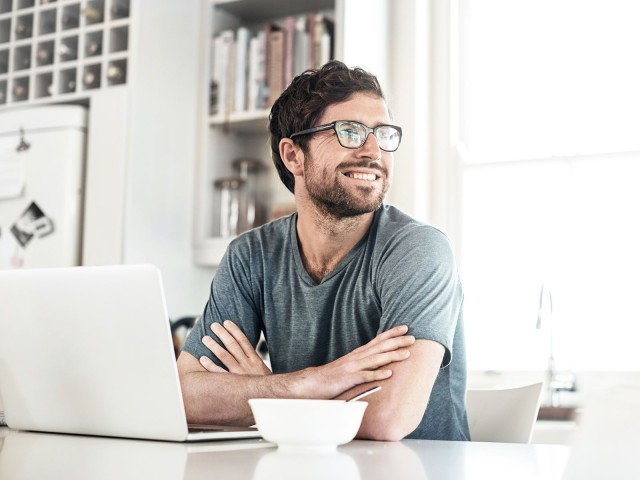 Mann an Laptop lächelt zufrieden: Zahlungsverkehrsmanagement bei der LBBW