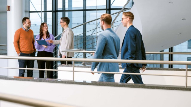 Personen unterhalten sich im Flur eines Bürogebäudes.