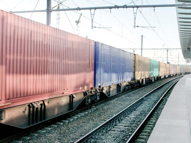 Zug mit Containern rollt am Bahnhof vorbei 
