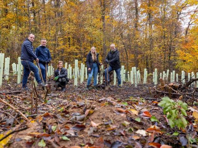 Five smiling people in the forest with shovels