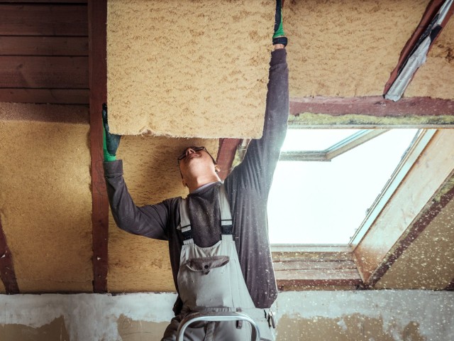 Handwerker baut Dämmung ans Dach