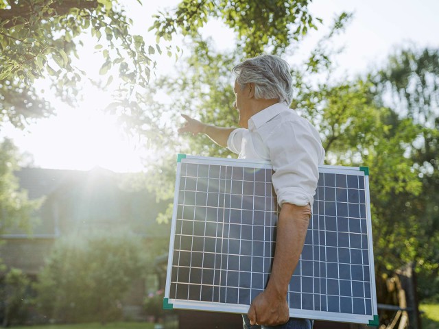 Ein Mann trägt eine Panel einer Solaranlage