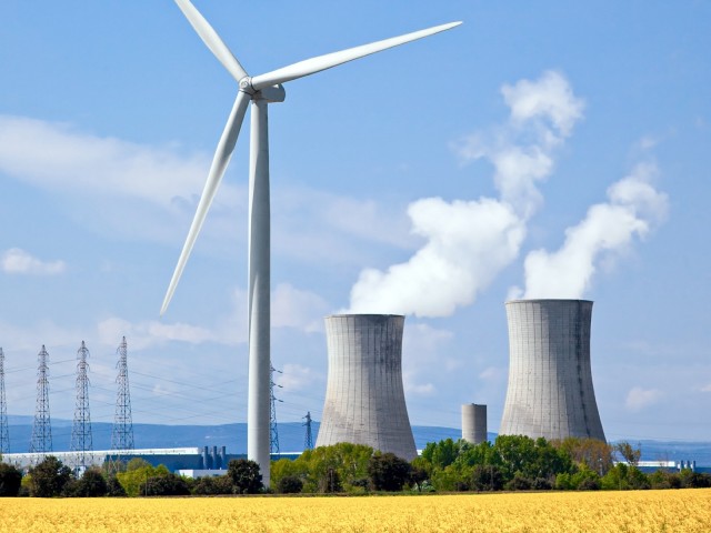 Windrad mit Rapsfeld im Vordergrund und Atomkraftwerk im Hintergrund