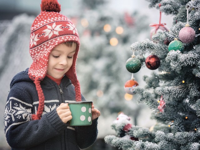 Boy in front of Christmas tree with cup