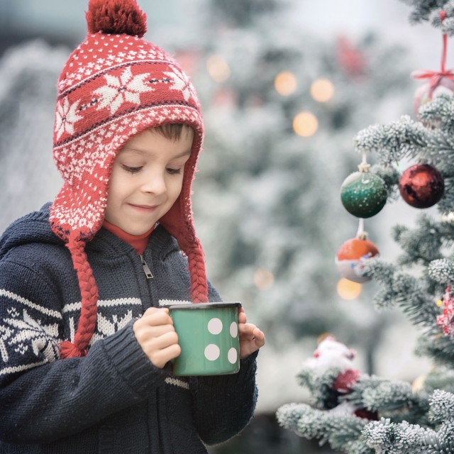 Boy in front of Christmas tree with cup