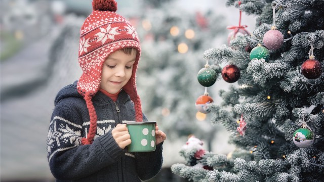 Boy in front of Christmas tree with cup