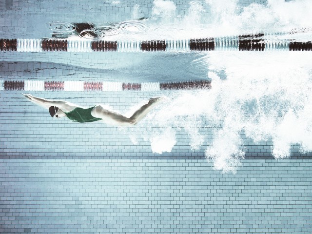 Schwimmerin springt in einen Pool, Unterwasseraufnahme